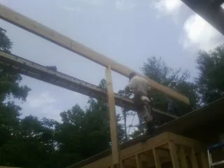 Carpenter setting a ridge beam over a new addition frame — Ice Dam Removal by Roofing Brothers in Iva