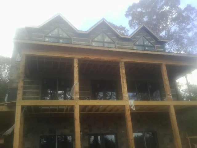 Dormers and porch framing on a large log home under construction — Roof Coating work by our crew in Iva