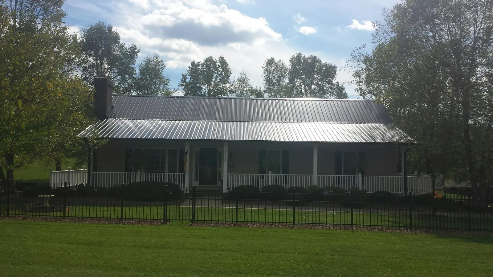 Gray metal roof on a brick ranch with a full width front porch — Gutter Guard Installation work by our crew in Iva